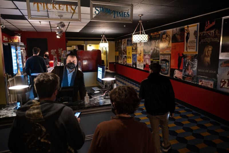 Christopher Escobar, owner of the Plaza Theatre, helps patrons while working the ticket counter Saturday night, Jan. 29, 2022 before a 35mm showing of “The Shining.”  Ben Gray for the Atlanta Journal-Constitution