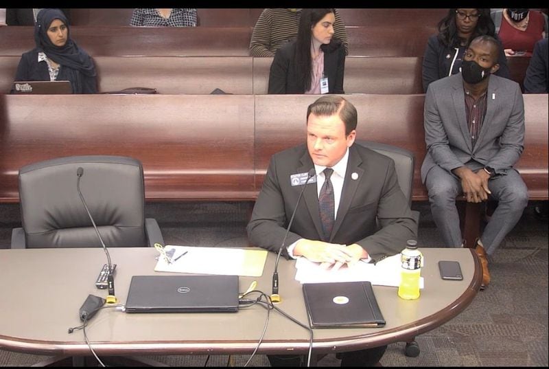 State Sen. Clint Dixon addresses a Senate panel concerning changes he wants in Gwinnett County elections. Gwinnett school board Chairman Everton Blair, seated behind him, opposes the measure.