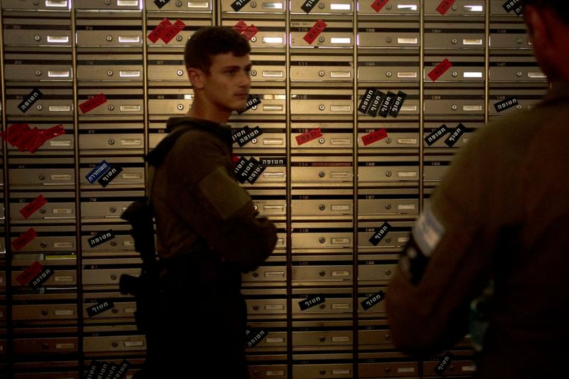 Israeli soldiers visit the mailroom in Kibbutz Nir Oz, where mailboxes are labeled with residents' status - killed (red), kidnapped (black), and released (blue) on Thursday, April 11, 2024, at the communal dining hall during a Passover seder event for hostages held in Gaza, at the kibbutz in southern Israel, where a quarter of all residents were killed or captured by Hamas on Oct. 7, 2023. For many Jews, no matter how observant, Passover is a time to unite with family to eat and drink around what's known as a Seder table, remembering how the Jews persevered through harsh times. But this year, when Passover begins on Monday, many families are torn on how to celebrate, or if it's worth acknowledging at all. (AP Photo/Maya Alleruzzo)