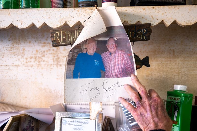 James “Soapy” Herndon displays a photo of him and Jimmy Carter at Soapy’s Barber Shop in Americus on Saturday, March 4, 2023. Herndon was longtime barber to Jimmy Carter. (Arvin Temkar / arvin.temkar@ajc.com)