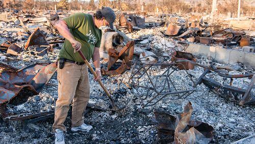 Ed Corn wears a mask as he sifts through the ashes of the home he shared with his paraplegic roommate in Santa Rosa’s Coffey Park neighborhood. “I can definitely taste the toxins in my throat and the back of my tongue,” he said. (Heidi de Marco/KHN/TNS)