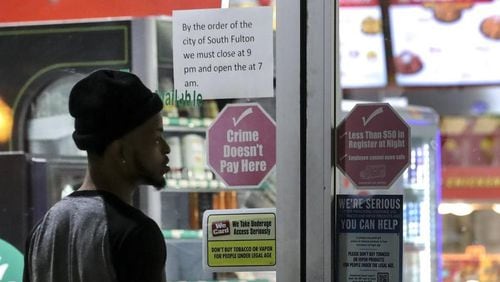 A sign lets customers know about the city of South Fulton’s curfew at 3515 Cascade Road on Thursday, March 19, 2020. JOHN SPINK/JSPINK@AJC.COM