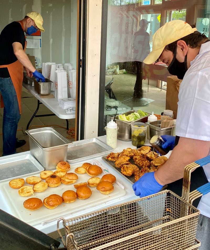 Greg Best (left) organizes orders at a Saturday morning pop-up, while partner Will Silbernagel makes sandwiches. Wendell Brock for The Atlanta Journal-Constitution