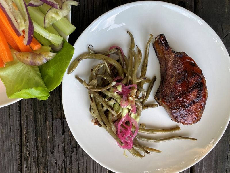 Empire State South offers a bone-in pork chop with black garlic barbecue sauce and a side of green beans with dill Mornay. An appetizer of crudités, which pairs nicely with the pimento cheese, is at upper left. Wendell Brock for The Atlanta Journal-Constitution