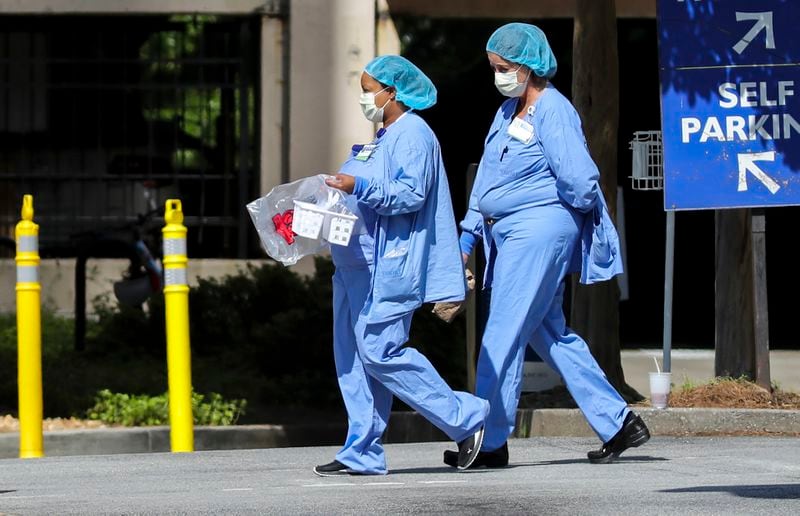 Medical workers, wearing masks to protect against the novel coronavirus, cross the campus of Emory University Hospital Midtown in Atlanta on Friday, April 17, 2020. JOHN SPINK/JSPINK@AJC.COM