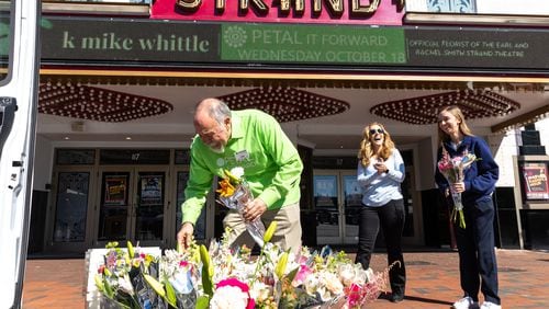 Florist K. Mike Whittle gives free flower bouquets to Kelly Ehrhardt (center) and Isabelle Geller (right) in Marietta Square on Wednesday, October 18, 2023. The event was part of the Society of American Florists' “Petal it Forward” goodwill initiative. (Arvin Temkar / arvin.temkar@ajc.com)