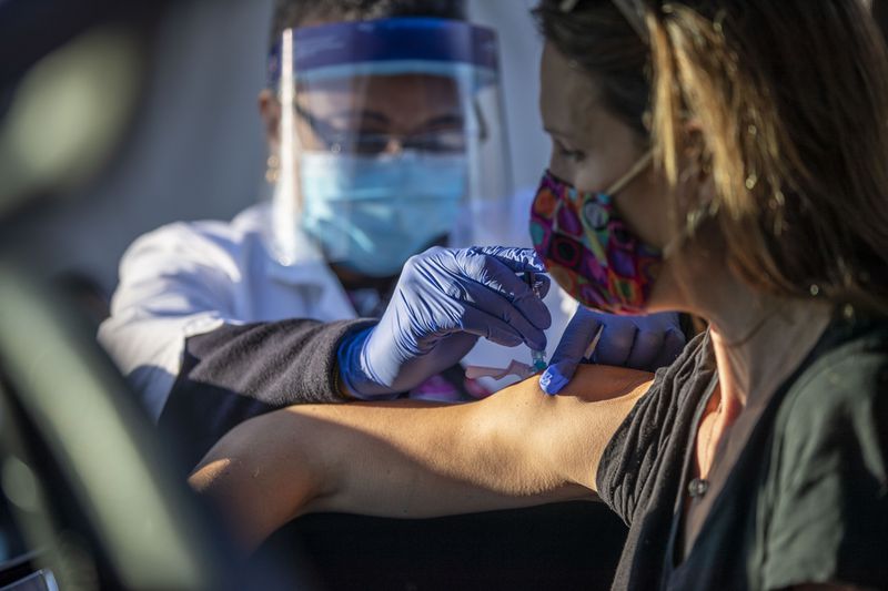 Nurse Stella Eziashi-Anaheim, Clinical Supervisor for North DeKalb Health Center,  gave a flu shot to Erica Coe during an October drive-thru flu shot distribution at the North DeKalb Health Center in Chamblee. (Alyssa Pointer / Alyssa.Pointer@ajc.com)