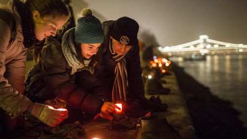 Backdropped by the illuminated Chain Bridge, people light candles in front of the cast iron shoes at the Holocaust Memorial on the quay of the River Danube, during International Holocaust Remembrance Day in Budapest, Hungary, Wednesday, Jan. 27, 2016. International Holocaust Remembrance Day marks the liberation of Auschwitz-Birkenau Nazi concentration camp by Soviet troops on Jan. 27, 1945.