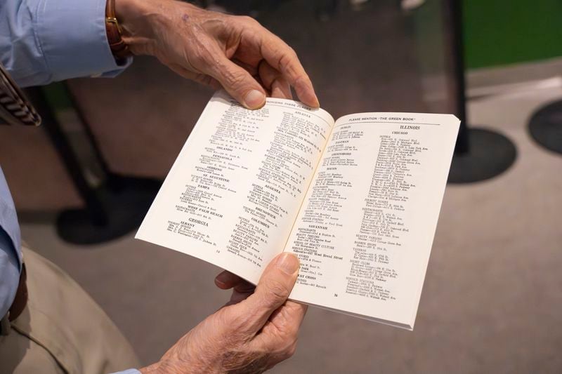 Tony Clark, director of public affairs for the Carter Center, holds a replica of a 1947 "The Negro Motorist Green Book," from the new exhibit, which opens Saturday, March 30, 2024. (Olivia Bowdoin for the AJC).