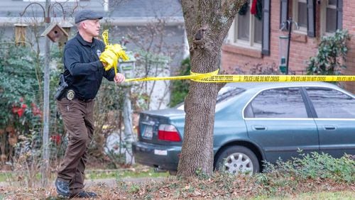 A Doraville police officer takes down the crime scene tape at a home on Beachwood Avenue where a 43-year-old man was discovered shot and killed early Thursday morning.