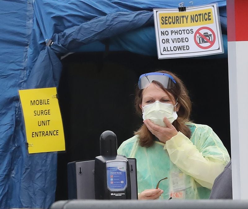 A nurse stands Tuesday at the entrance to the mobile surge unit tent outside the emergency entrance at WellStar Kennestone Hospital. Curtis Compton ccompton@ajc.com