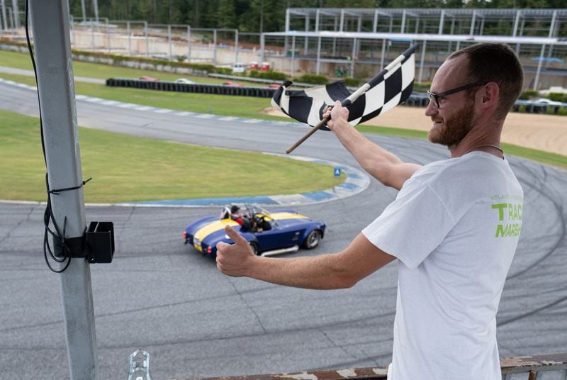 Brent Landry waves the checkered flag as cars circle Atlanta Motorsports Park in Dawsonville  during Ferrari of Atlanta’s annual Rides to Remember 2021 event Saturday morning, Sept. 18, 2021. (Photo: Ben Gray for The Atlanta Journal-Constitution)