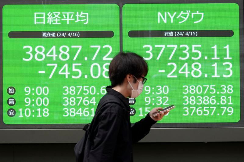 A person walks in front of an electronic stock board showing Japan's Nikkei and New York Dow indexes at a securities firm Tuesday, April 16, 2024, in Tokyo. (AP Photo/Eugene Hoshiko)