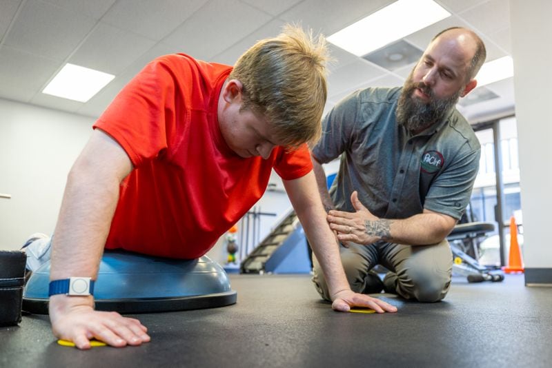 Coach Dustin Dalton (right) works with Davis Manton at the ReClif fitness-based therapy center in Peachtree Corners Tuesday, Feb. 14, 2023.  (Steve Schaefer/steve.schaefer@ajc.com)