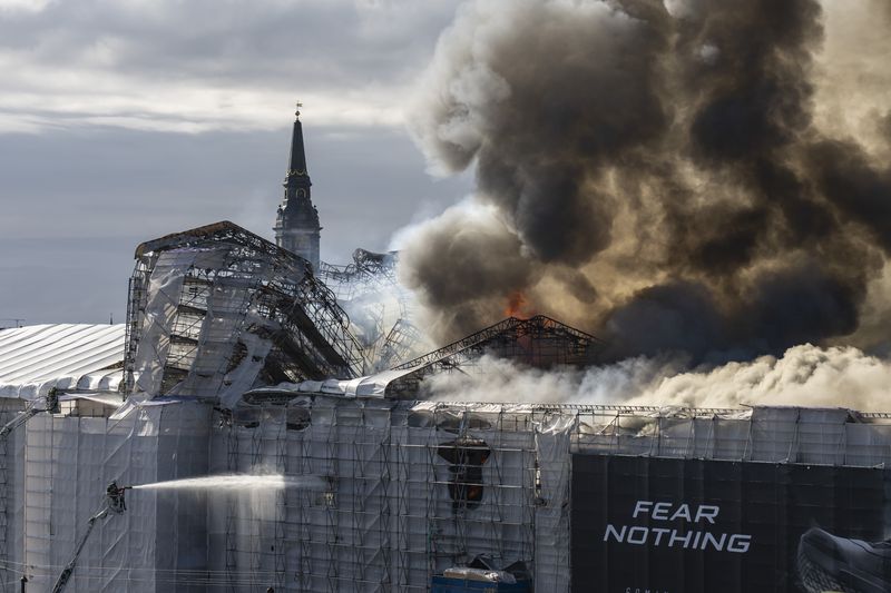 Firefighters work as smoke rises out of the Old Stock Exchange in Copenhagen, Denmark, Tuesday, April 16, 2024. A fire raged through one of Copenhagen’s oldest buildings on Tuesday, causing the collapse of the iconic spire of the 17th-century Old Stock Exchange as passersby rushed to help emergency services save priceless paintings and other valuables. (Emil Nicolai Helms/Ritzau Scanpix via AP)