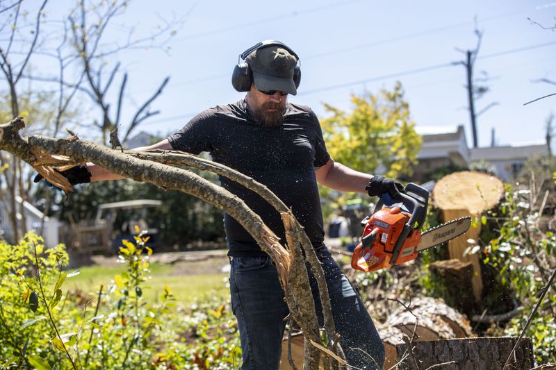 Jason Rose cleans up downed trees in the backyard of his mother’s property in Newnan. Volunteers have fanned out across Newnan to help, cleaning up debris and delivering meals. (Alyssa Pointer / Alyssa.Pointer@ajc.com)