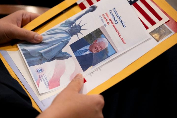 A woman holds her packet of information and a program before being sworn in as a naturalized citizen at The Carter Center in Atlanta on Sunday, Oct. 1, 2023. The ceremony was held at the center in honor of President Jimmy Carter’s 99th birthday.   (Ben Gray / Ben@BenGray.com)