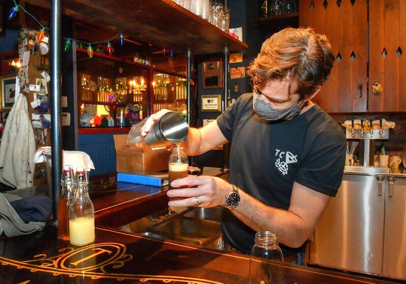 Ticonderoga Club co-owner Paul Calvert mixes and fills bottles for to-go cocktails made to order from the walk-up window at the club, during a closure caused by two staff members testing positive for COVID. (Chris Hunt for The Atlanta Journal-Constitution)