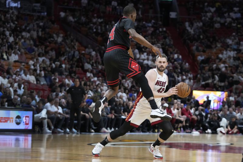 Miami Heat forward Kevin Love (42) avoids a block by Chicago Bulls guard Javonte Green (24) during the first half of an NBA basketball play-in tournament game, Friday, April 19, 2024, in Miami. (AP Photo/Wilfredo Lee)