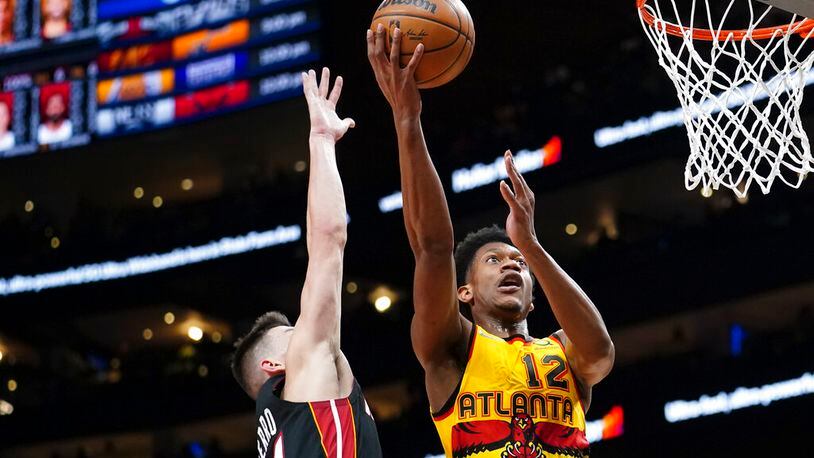 Hawks forward De'Andre Hunter (12) goes up for a shot as Miami Heat guard Tyler Herro (14) defends during the first half of an NBA basketball game Wednesday, Jan. 12, 2022, in Atlanta. Hunter was playing in his first game since undergoing wrist surgery. (AP Photo/John Bazemore)