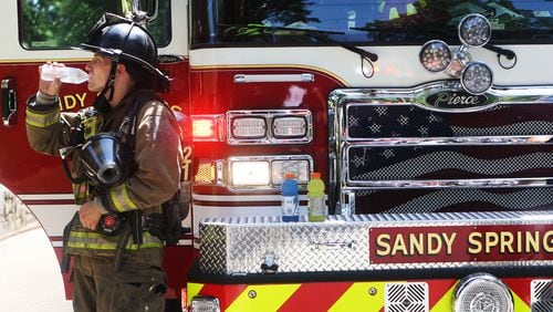 An image of a Sandy Springs firefighter  during summer 2019 sipping water at the site of a hazardous material incident on the 3300 block of Habersham Road NW in Buckhead. Sandy Springs Public Safety so far has had one confirmed case of COVID-19 among its nearly 330 police and firefighters, but the department is monitoring 25 others who may have been exposed on the job or elsewhere.CHRISTINA MATACOTTA/CHRISTINA.MATACOTTA@AJC.COM