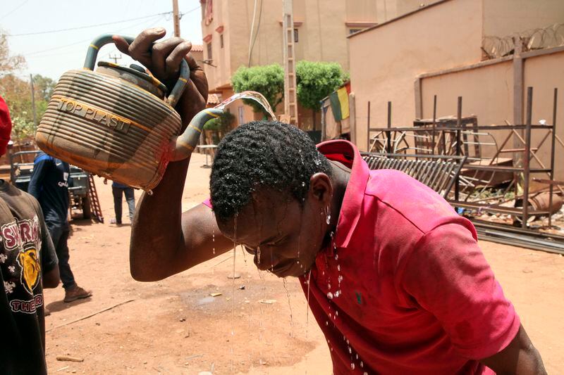 Soumaila Traoré, a 30-years-old welder, cools off with water under a blazing sun in Bamako, Mali, Thursday, April, 18, 2024. On Thursday, temperatures in Bamako reached 44 degrees Celsius (111 Fahrenheit) and weather forecasts say it's not letting up anytime soon. (AP Photo/Baba Ahmed)