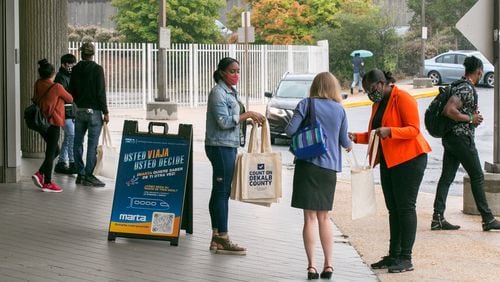 DeKalb County Election officials including Lamashia Davis, center, and Erin Austin, right, in orange, work to spread information about changes in voter laws and offer free voter IDs, if needed, on Wednesday, Sept 15, 2021 at the Chamblee MARTA Station.  (Jenni Girtman for The Atlanta Journal-Constitution)