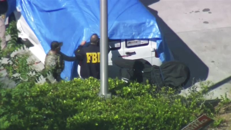 In this frame grab from video provided by WPLG-TV, FBI agents cover a van parked in Plantation, Fla., on Friday, Oct. 26, 2018, that federal agents and police officers have been examining in connection with package bombs that were sent to high-profile critics of President Donald Trump. The van has several stickers on the windows, including American flags, decals with logos and text. (WPLG-TV via AP)