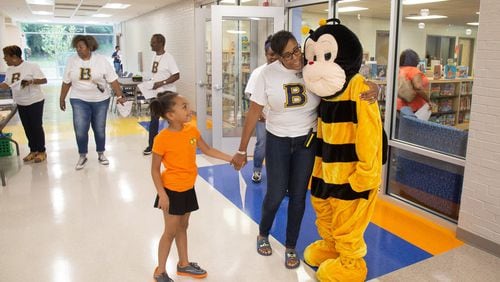 Beecher Hills Elementary school principal Crystal Jones (C) hugs the schools’ mascot while holding the hand of Olivia Sorel during the first open house after the schools’ extensive renovation Friday, August 9, 2019. STEVE SCHAEFER / SPECIAL TO THE AJC