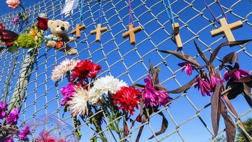 Crosses and flowers hang on a fence outside Marjory Stoneman Douglas High School in Parkland, Florida, in memory of the 17 people killed in a shooting. Attorneys for the man accused of killing 17 people at a Florida high school in 2018 want a judge to close all future hearings to the media and the public to ensure a fair trial. (AJC file photo)