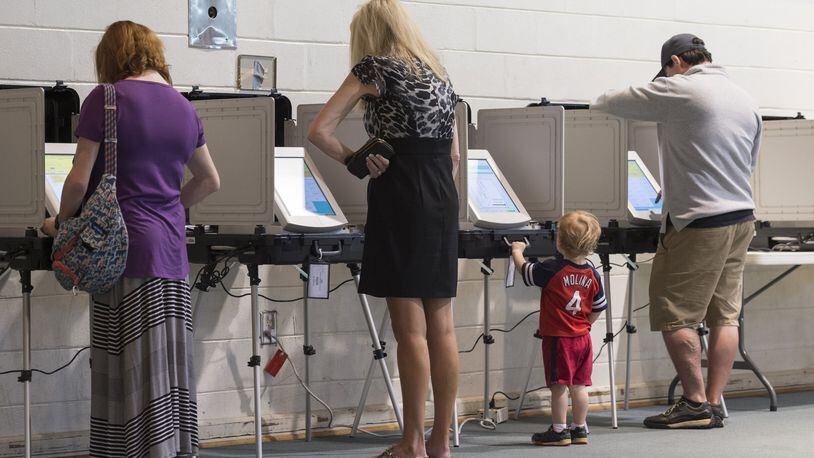 A.J. Seger, 2, stands at a voting machine while his mother, Mindy Seger, far left, casts her ballot at Mount Zion United Methodist Church in Marietta on April 18, during the first round of voting to fill the empty U.S. House seat representing Georgia’s 6th Congressional District. (DAVID BARNES / DAVID.BARNES@AJC.COM)