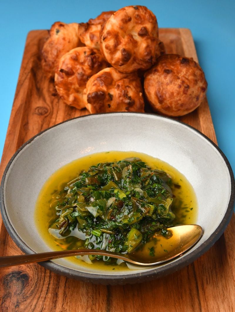 One of the ways to use Spring Vidalia Greens Chimichurri (in bowl) is to serve it with Spring Vidalia Pão de Queijo (Brazilian cheese bread). Both are from executive chef Joey Ward of Southern Belle and Georgia Boy. (Styling by Joey Ward / Chris Hunt for the AJC)