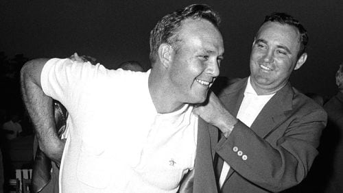 Arnold Palmer dons with first green jacket, with the help of Doug Ford, after winning the 1958 Masters.