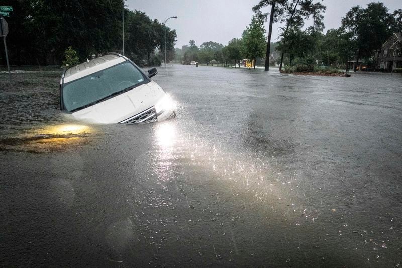 An SUV is stranded in a ditch in a stretch of street flooding during a severe storm, Thursday, May 2, 2024, in Spring, Texas. (Brett Coomer/Houston Chronicle via AP)