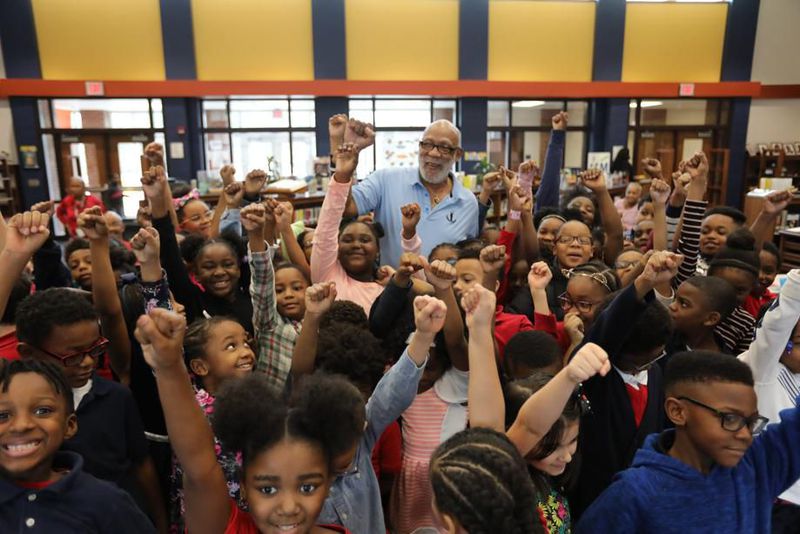 After his talk, students surrounded John Carlos to take a picture, and he invited them to raise their fists, emulating what he did in the 1968 Mexico Olympics, at Barack H. Obama Elementary Magnet School of Technology on Wednesday, Feb. 26, 2020 in Atlanta. MIGUEL MARTINEZ for the AJC
