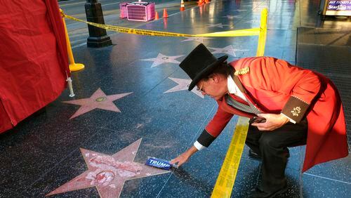 Gregg Donovan, who calls himself the unofficial ambassador of Hollywood, places a sticker for Republican presidential candidate Donald Trump on Trump's vandalized star on the Hollywood Walk of Fame, Wednesday, Oct. 26, 2016 in Los Angeles. Det. Meghan Aguilar said investigators were called to the scene before dawn Wednesday following reports that Trump's star was destroyed by blows from a hammer. (AP Photo/Richard Vogel)