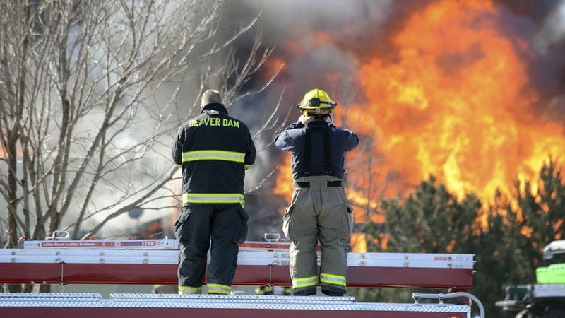 Firefighters stand atop a truck while watching flames burn a building at the Village Glen Apartments in Beaver Dam, Wisconsin, Thursday, March 15, 2018. The fire was set to destroy hazardous chemicals in a building where Benjamin Morrow accidentally blew himself up 10 days earlier in his apartment. Morrow had finished explosives, the chemicals to make bombs, guns, ammunition and white supremacist literature in his apartment, according to search warrants.