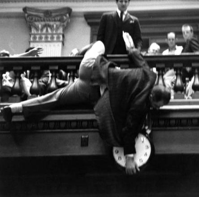 In 1964, state Rep. Denmark Groover, a Democrat from Macon, scooted out on a railing above the House floor to stop the chamber’s clock, hoping to avoid a mandatory midnight adjournment before a vote was taken on a redistricting bill. (AJC file photo)