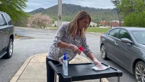 Shanda Ginn, owner and operator of Cleveland Academy in White County, disinfected a food cart she was using to distribute food to her enrolled children on March 31. She had closed her school a week earlier, after the state issued a coronavirus-related order that restricted the number of people in day care classrooms. She was still giving away “grab-n-go” meals to the parents who drove to her school. CONTRIBUTED BY MACY THOMPSON / CLEVELAND ACADEMY