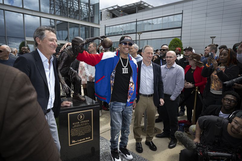 Former Philadelphia 76ers NBA basketball player Allen Iverson, center, poses for photos next to his statue at the teams training center in Camden, N.J., Friday, April 12, 2024 (Jose F. Moreno/The Philadelphia Inquirer via AP)