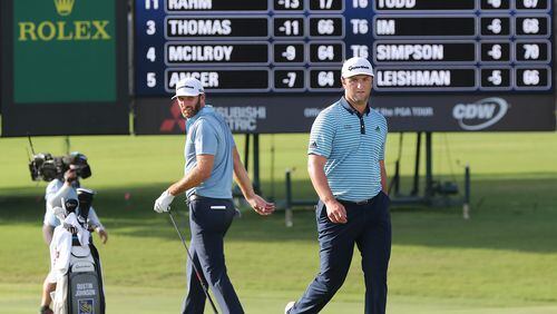 The leaders tied at 13 under par Dustin Johnson (left) and Jon Rahm (right) check out their shots on the 18th green during the first round of the Tour Championship at East Lake Golf Club on Friday, Sept. 4, 2020 in Atlanta.  Curtis Compton / Curtis.Compton@ajc.com