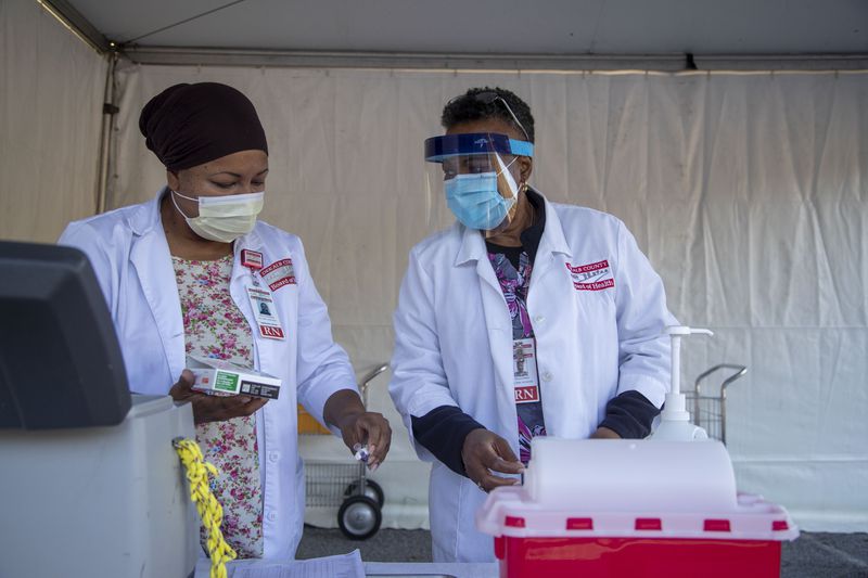 Nurse Stella Eziashi-Anaheim (right), clinical supervisor for North DeKalb Health Center, and nurse Shelia Alexander (left) prepare flu shots during a drive-thru flu clinic at the North DeKalb Health Center in Chamblee.  (Alyssa Pointer / Alyssa.Pointer@ajc.com)