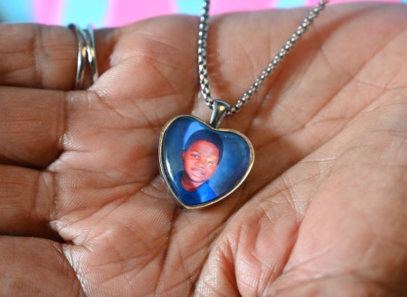 Glenda Mack holds a necklace she wears to remember her grandson, David. “We’re just praying, and I talk to David every night," she says. "It’s rough, but we’re coping. We gotta cope because we don’t have just ourselves to think about.” (Hyosub Shin / Hyosub.Shin@ajc.com)