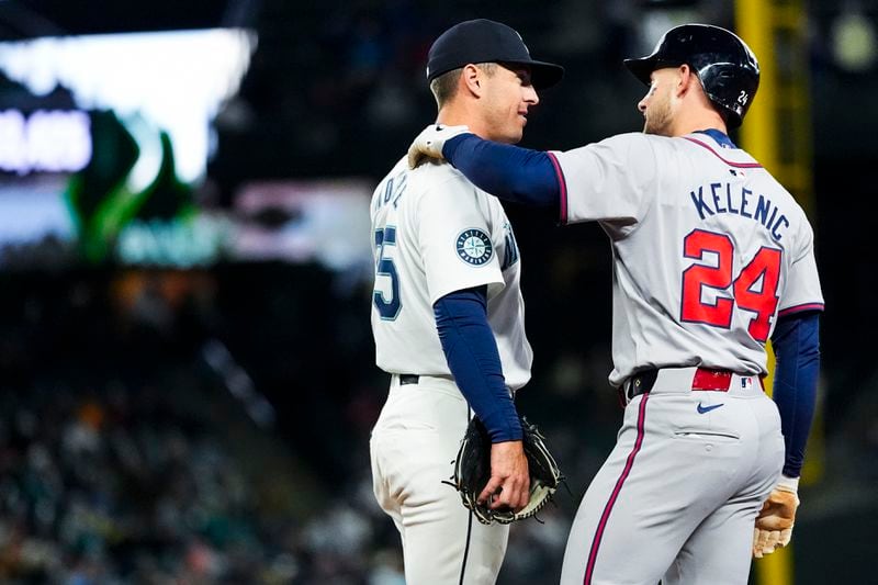 Seattle Mariners shortstop Dylan Moore, left, talks with Atlanta Braves' Jarred Kelenic, right, as they wait for a video review on whether Kelenic was out at first base during the third inning of a baseball game Monday, April 29, 2024, in Seattle. (AP Photo/Lindsey Wasson)