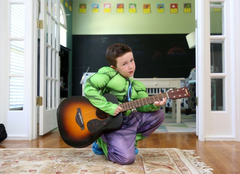 Joshua Davis, 5, wears a Hulk costume and plays the guitar at his Johns Creek home June 27, 2017. Joshua is a superhero in a real-life way: He has become an activist for his father, Mat, and others who have Alzheimer’s. The Davis family recently went to D.C. and talked with politicians about the cause. CONTRIBUTED BY JASON GETZ