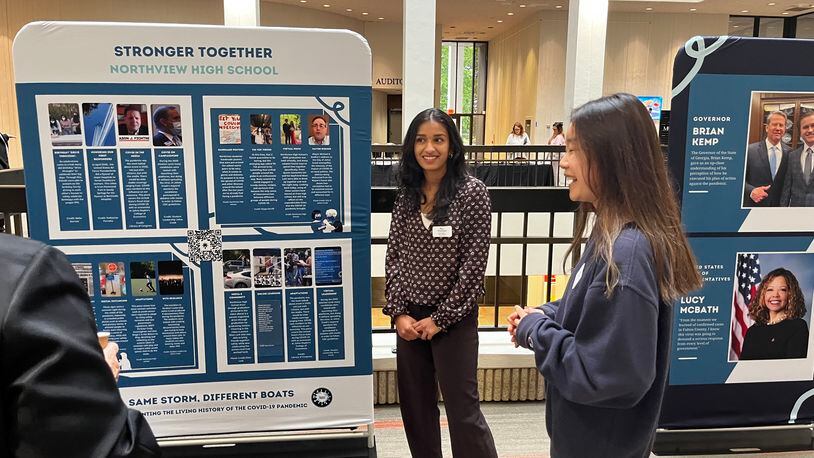 Northview High students Riya Havanur (center) and Irene Huang showcase the work they did with Student Leadership Johns Creek to document the pandemic's impact.