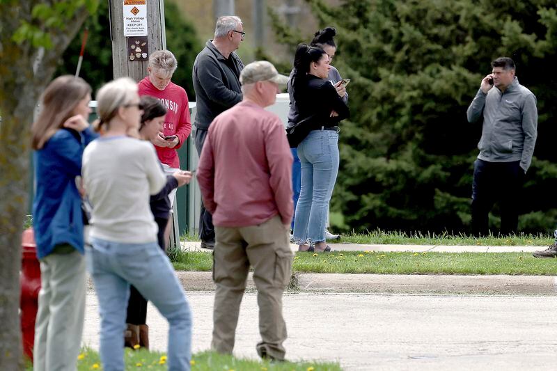 Bystanders watch as law enforcement personnel respond to the report of a person armed with a rifle at Mount Horeb Middle School in Mount Horeb, Wis., Wednesday, May 1, 2024. The school district said a person it described as an active shooter was outside a middle school in Mount Horeb on Wednesday but the threat was “neutralized” and no one inside the building was injured. (John Hart/Wisconsin State Journal via AP)