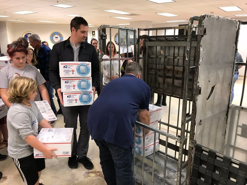  Tommy Owen helps put in the first boxes of letters into the post office containers. Brian Moote is on the left. CREDIT: Rodney Ho/rho@ajc.com