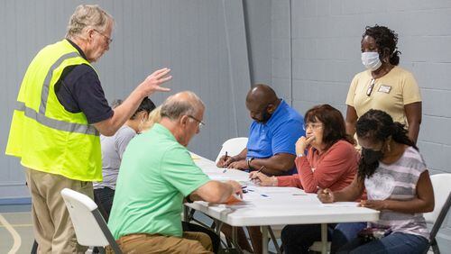 Rick Sloss (L)  helps voters fill out their paperwork on election day at GraceLife Church in Marietta Tuesday morning, May 24, 2022. (Steve Schaefer / steve.schaefer@ajc.com)