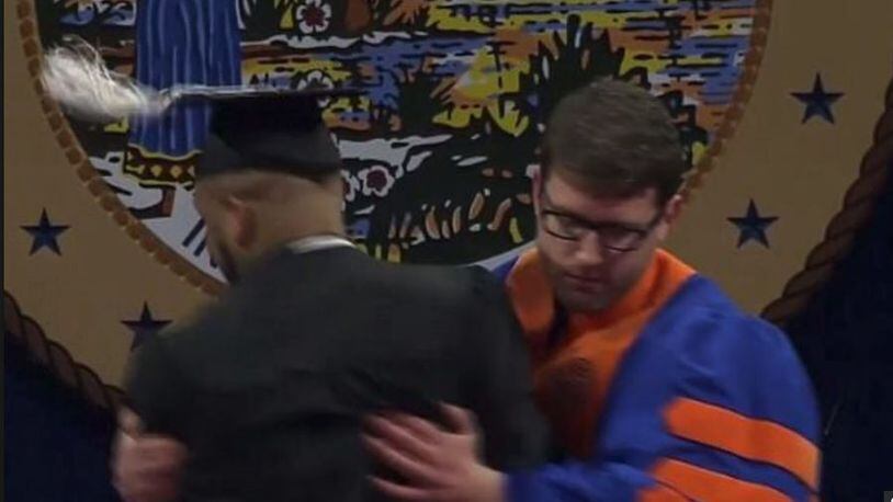 This screen grab from the University of Florida graduation shows a faculty member forcibly rushing a graduate off the stage after the student danced his way to his diploma. The university has apologized and the faculty member placed on leave.